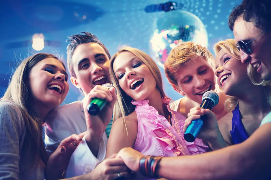Amigos cantando karaoke y pasando el micrófono en una fiesta